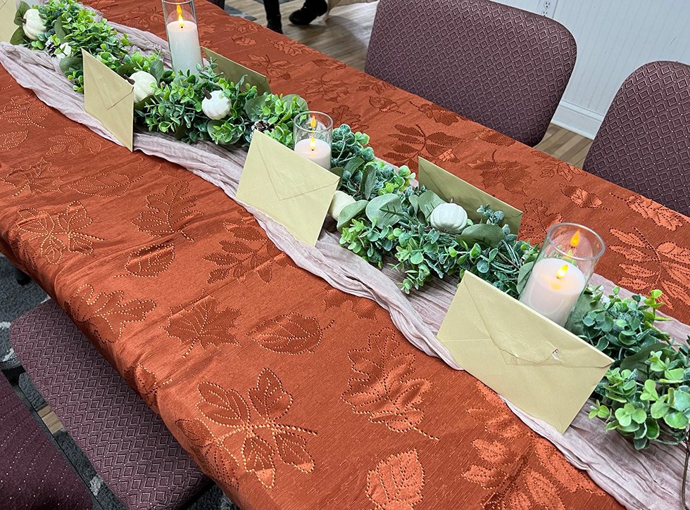 The table is decorated for the Coastal Prep Thanksgiving Dinner along with cards and donations for the students.